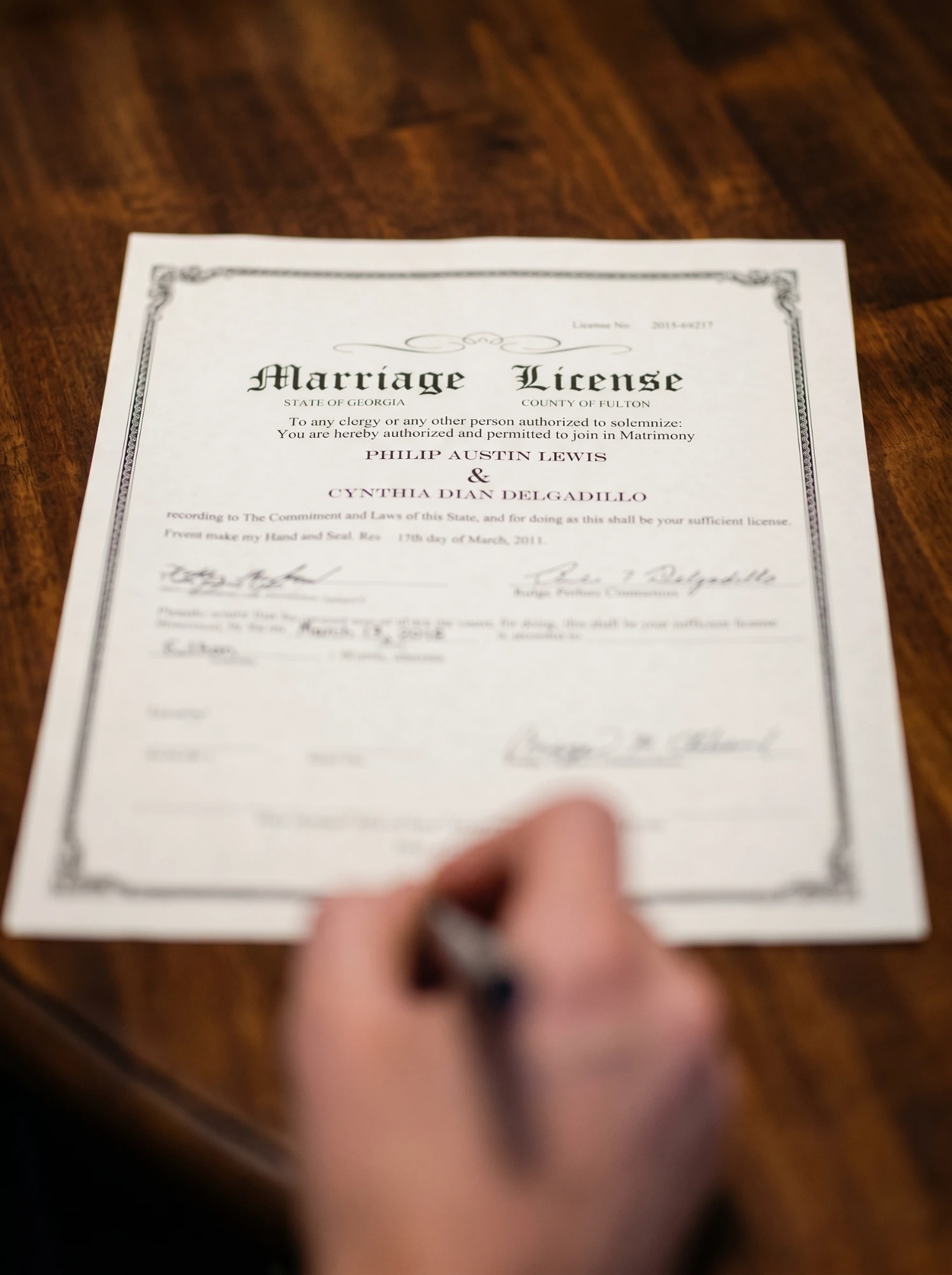 Close-up of a State of Georgia, Fulton County marriage license being signed with a pen — marriage-based green card