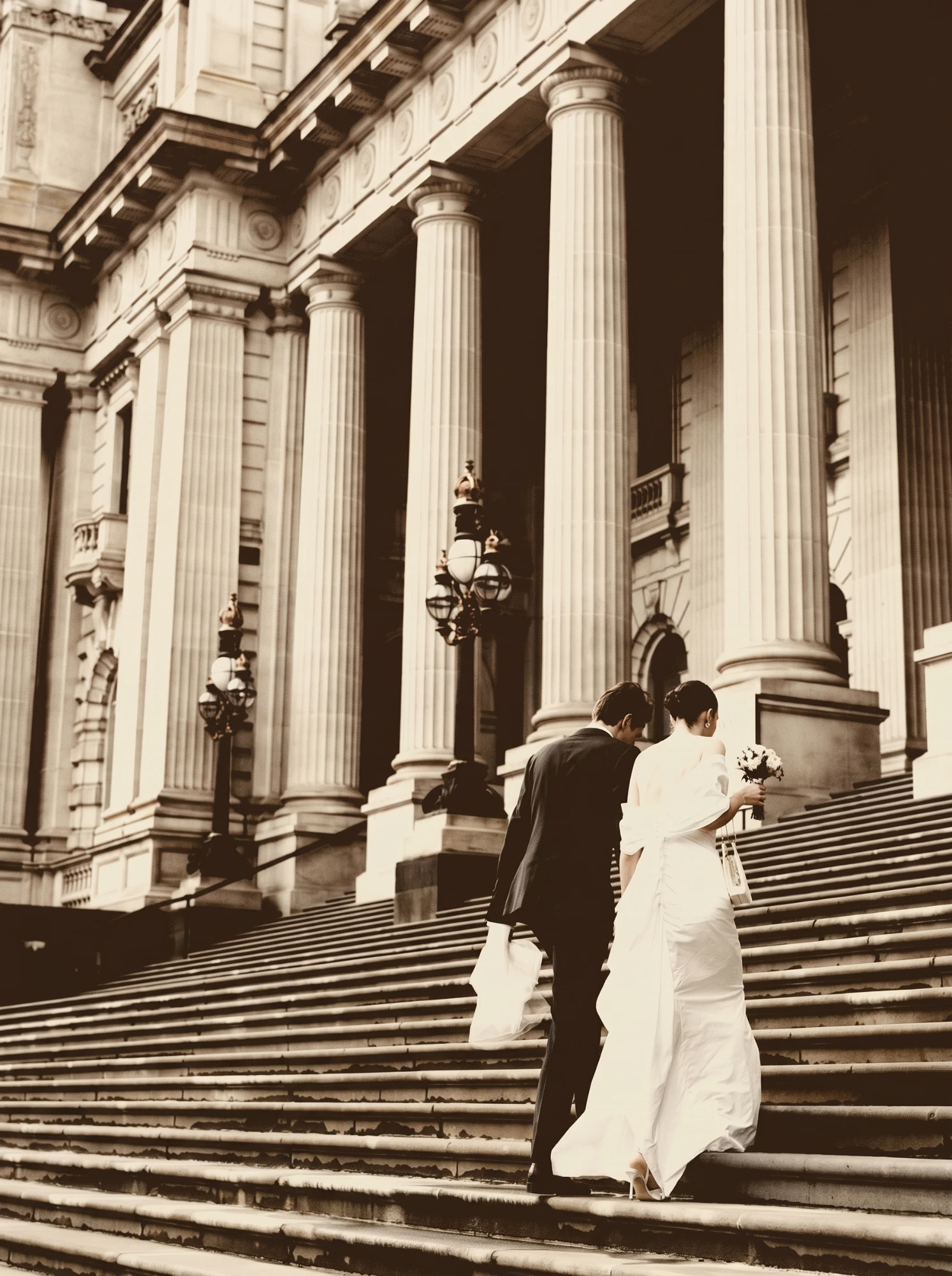 Bride and groom ascending the grand columned steps of a courthouse — family-based immigration